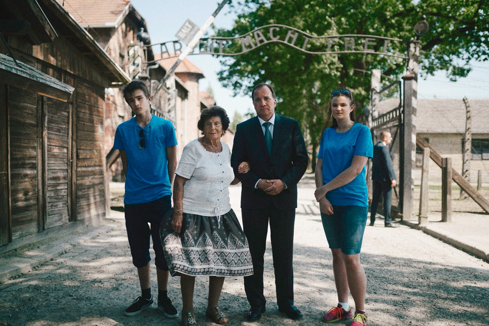 Four visitors standing beneath the entrance gate at Auschwitz